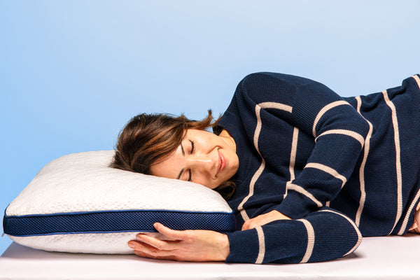 Photo of a woman laying on her side with her head on a thick white pillow with a dark blue mesh gusset
