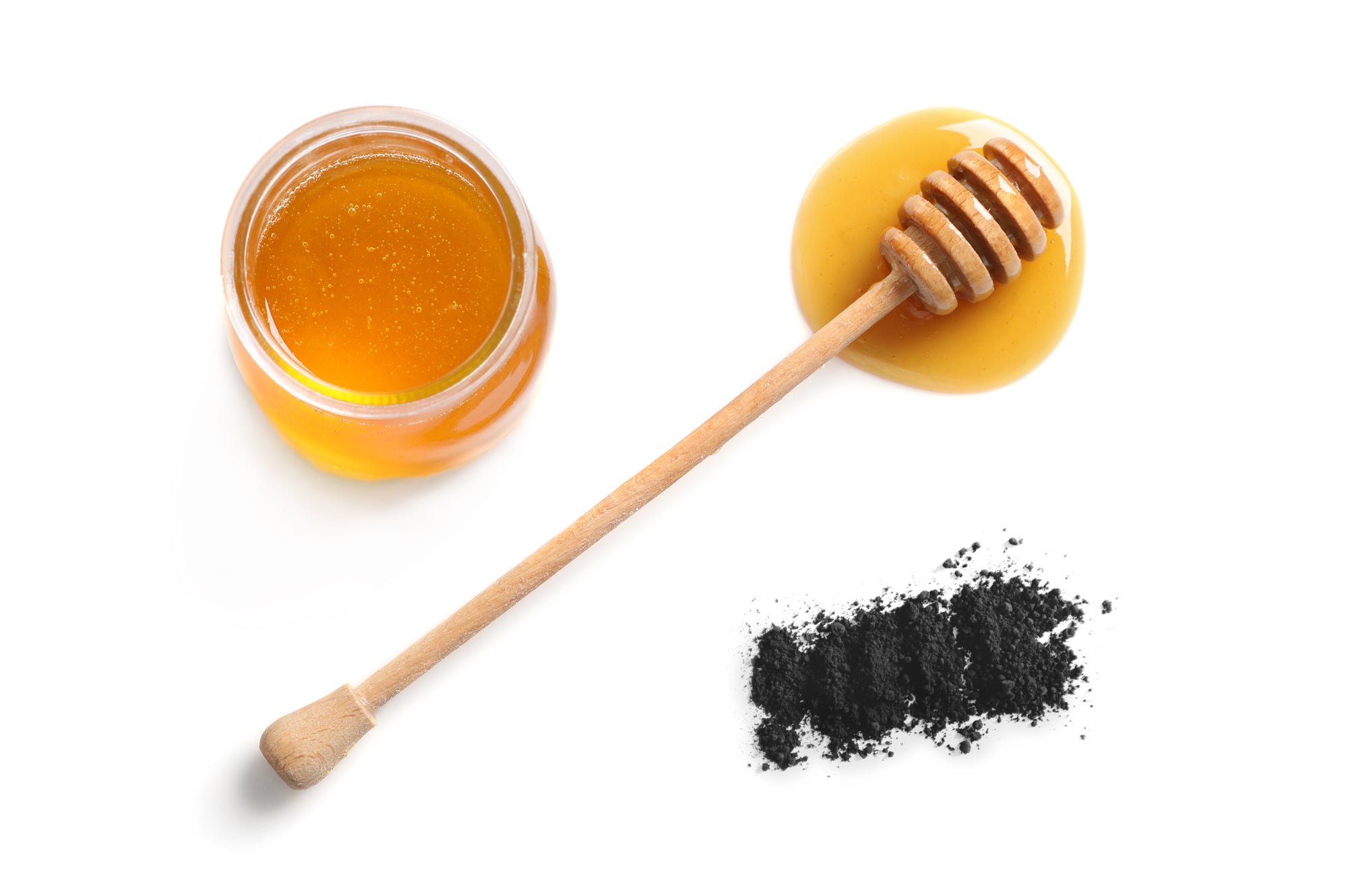 Photo of a jar of honey beside a teaspoon of activated charcoal