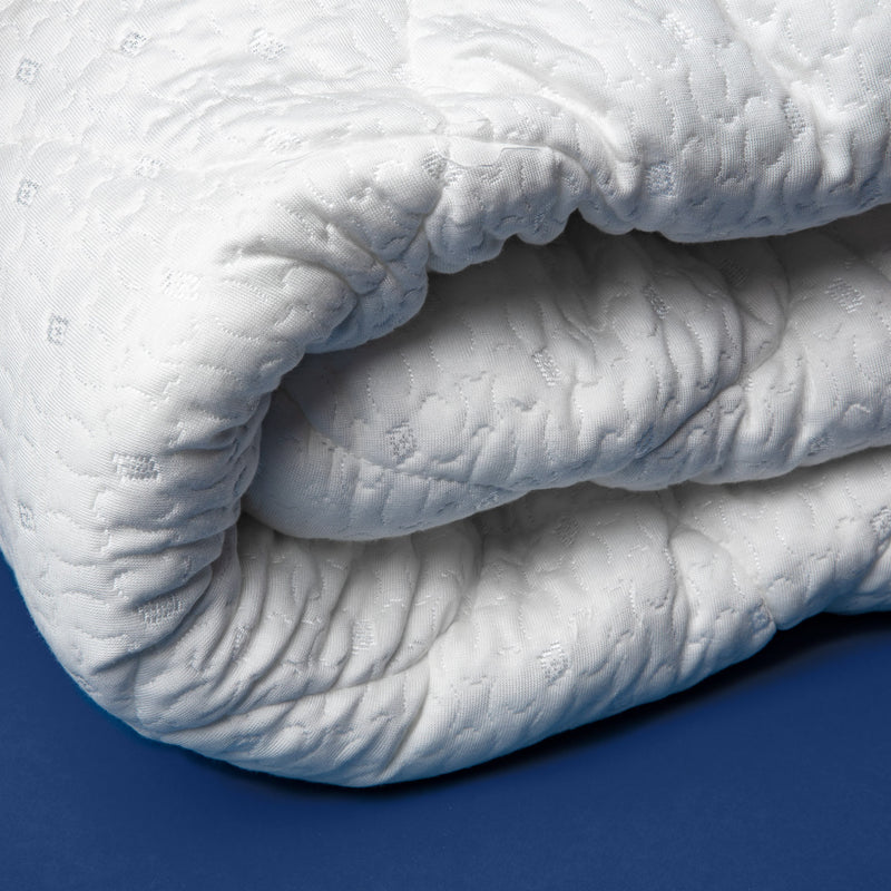 Close up view of a folded white pillow top mattress pad.