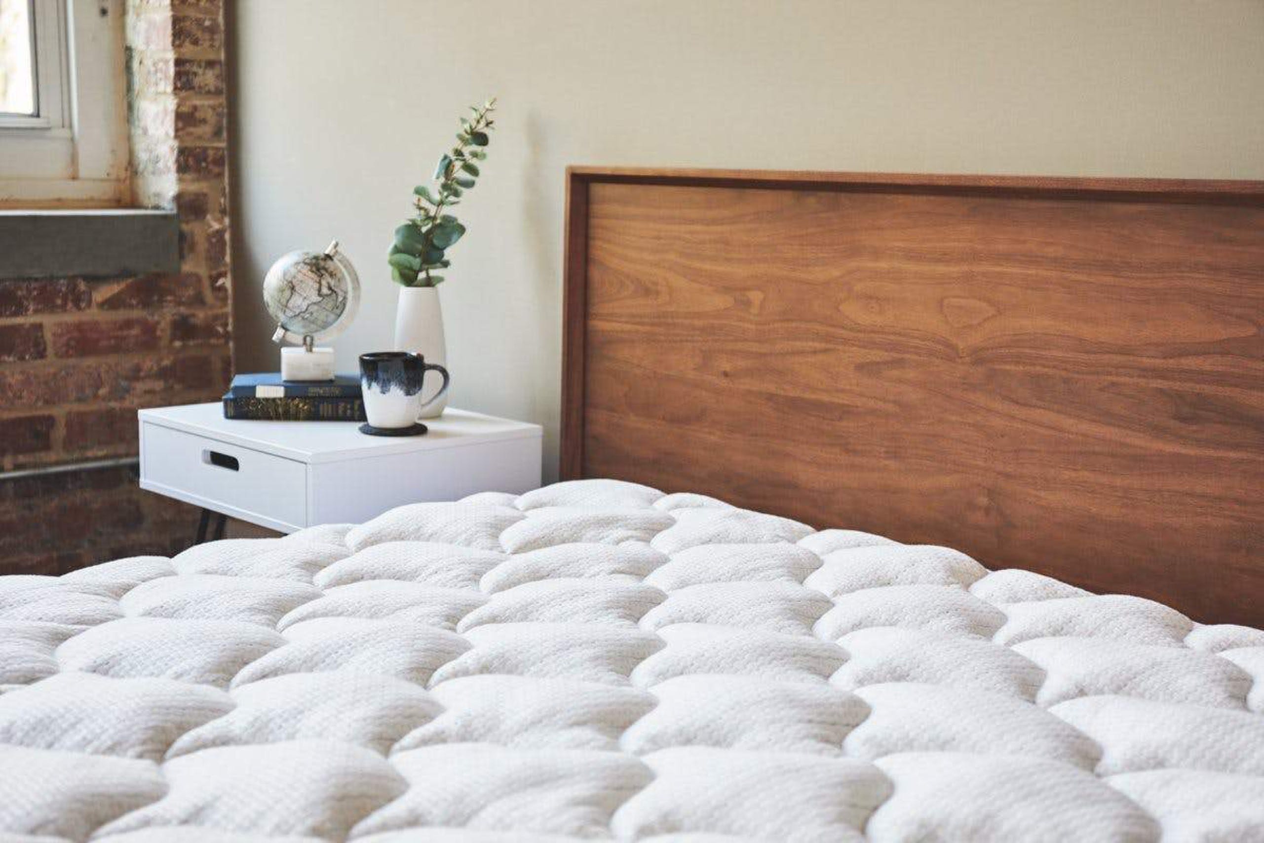 A bed equipped with a thick, white quilted mattress pad