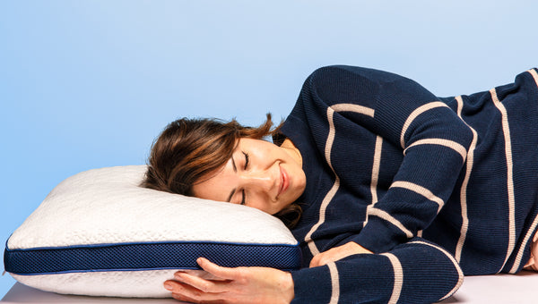 Photo of a woman laying on her side with her head on a thick white pillow with a dark blue mesh gusset
