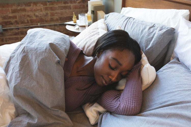 Woman lying down under a duvet cover resting her head on her arm