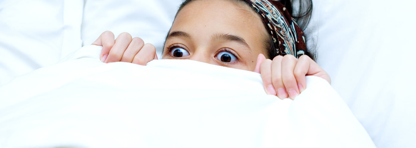 A child who looks scared and hiding under blankets