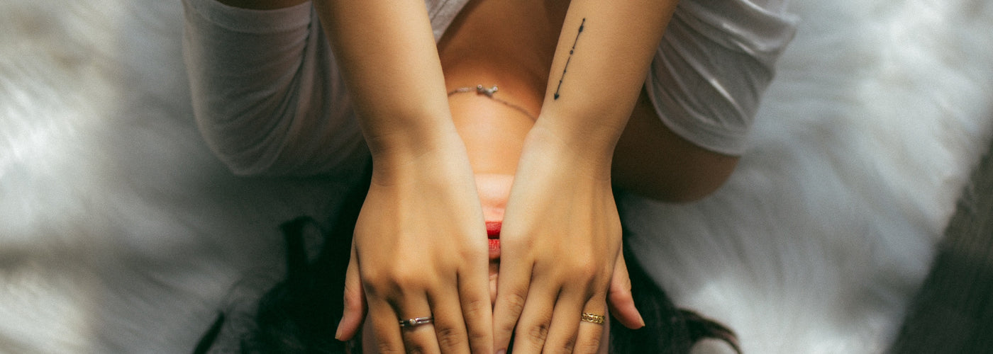 Woman laying on her bed covering her face with her hands