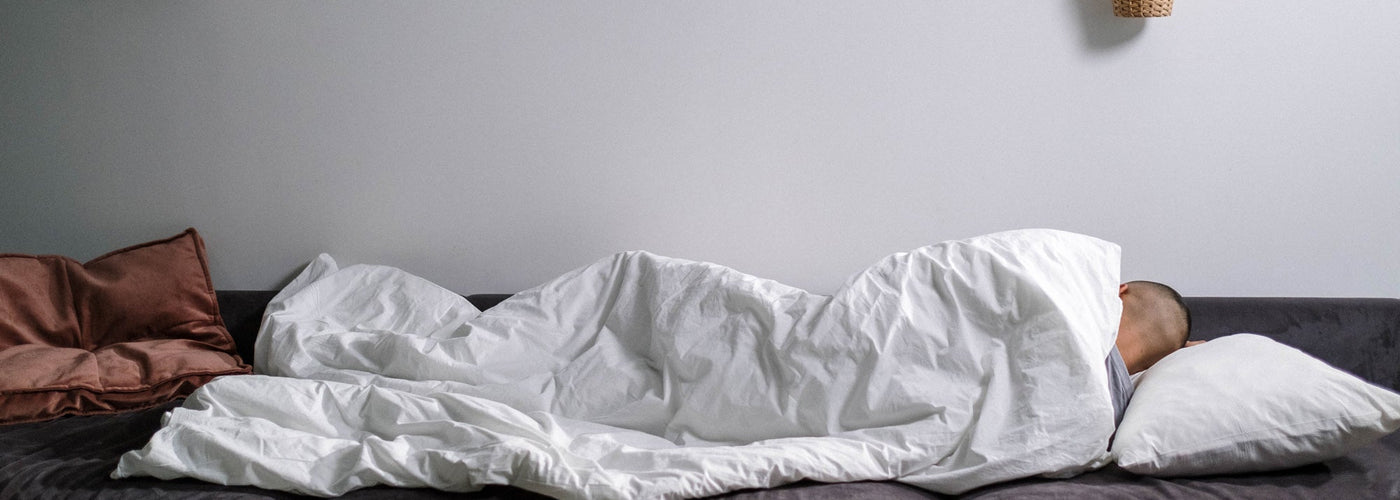 Photo of a person wrapped in a comforter while sleeping on a sofa