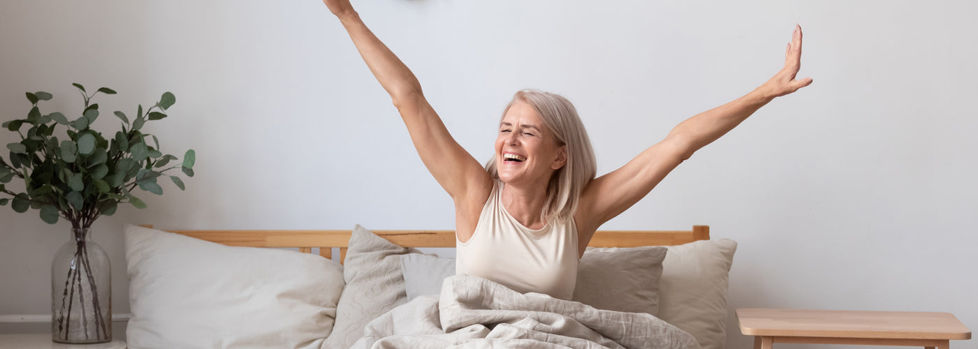 Woman stretching and smiling while waking up in bed