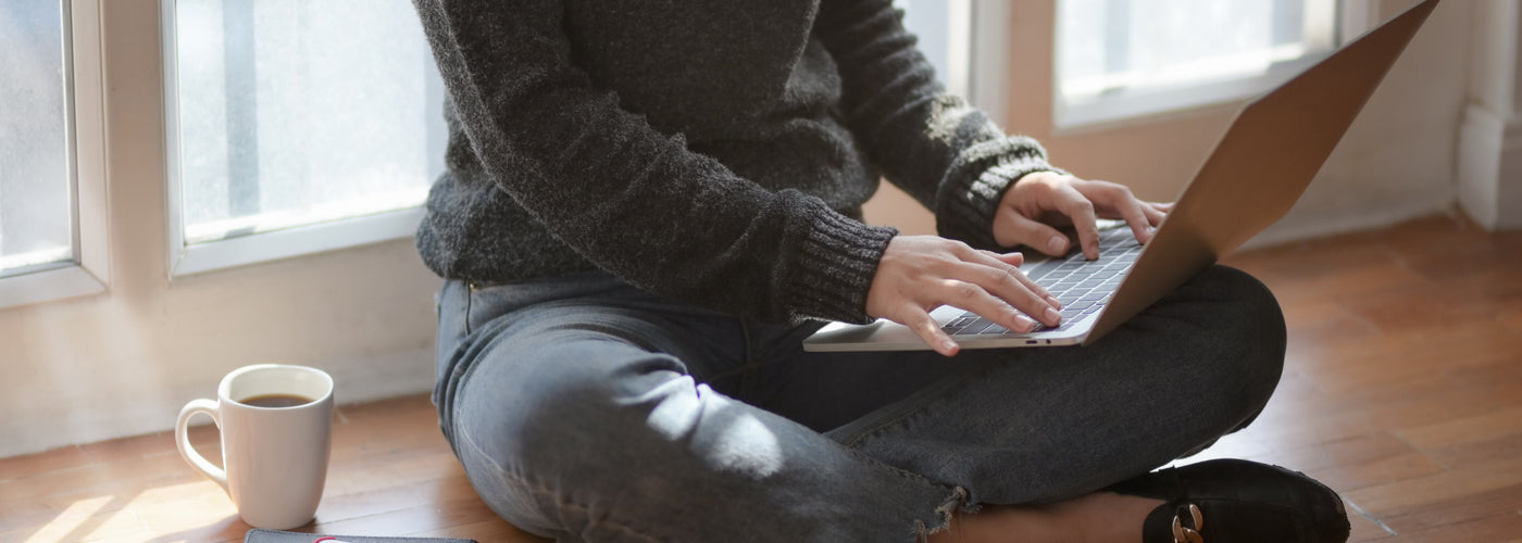 Professional woman working from home sitting on floor with a laptop