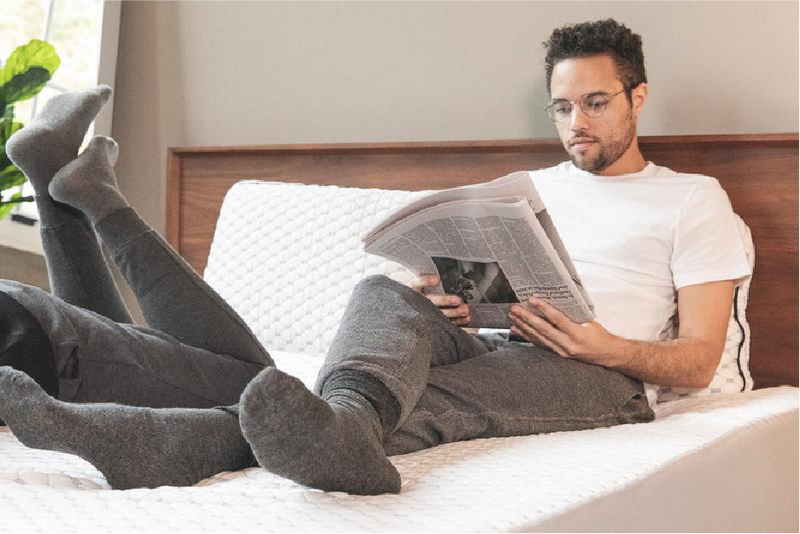man sitting on bed reading the paper