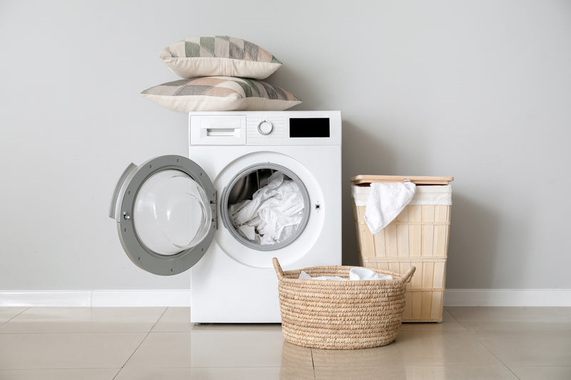 Front-load washing machine with door open to see mattress pad inside ready for laundering