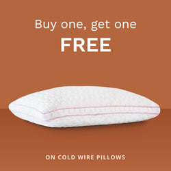 Buy one, get one FREE on all cold wire pillows. Photo of a white pillow with pink piping.