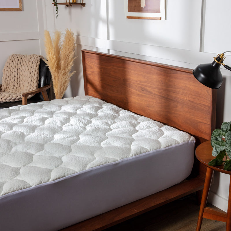 Photo of a white pillow top mattress pad fitted on a mattress.